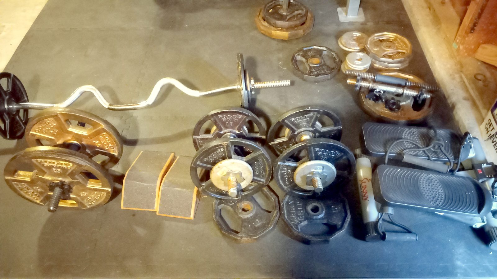 Plates, EZ curl bar and attachments on the floor